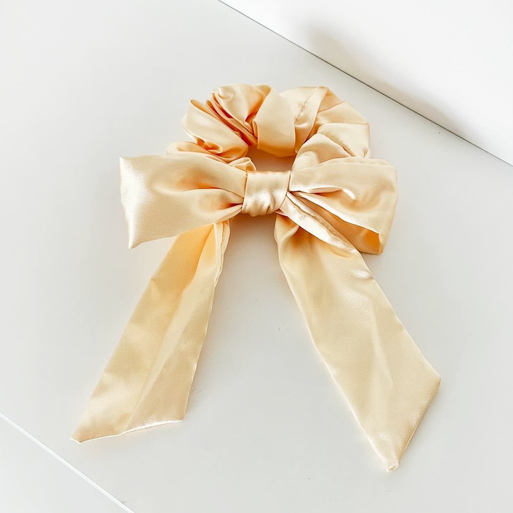 Butter yellow satin bow scrunchie with long, flowing tails and a smooth, shiny finish.