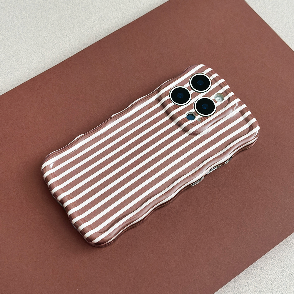 A smartphone in a wavy-edged case with brown and white vertical stripes lies on a brown surface. The camera section of the case matches the striped pattern.