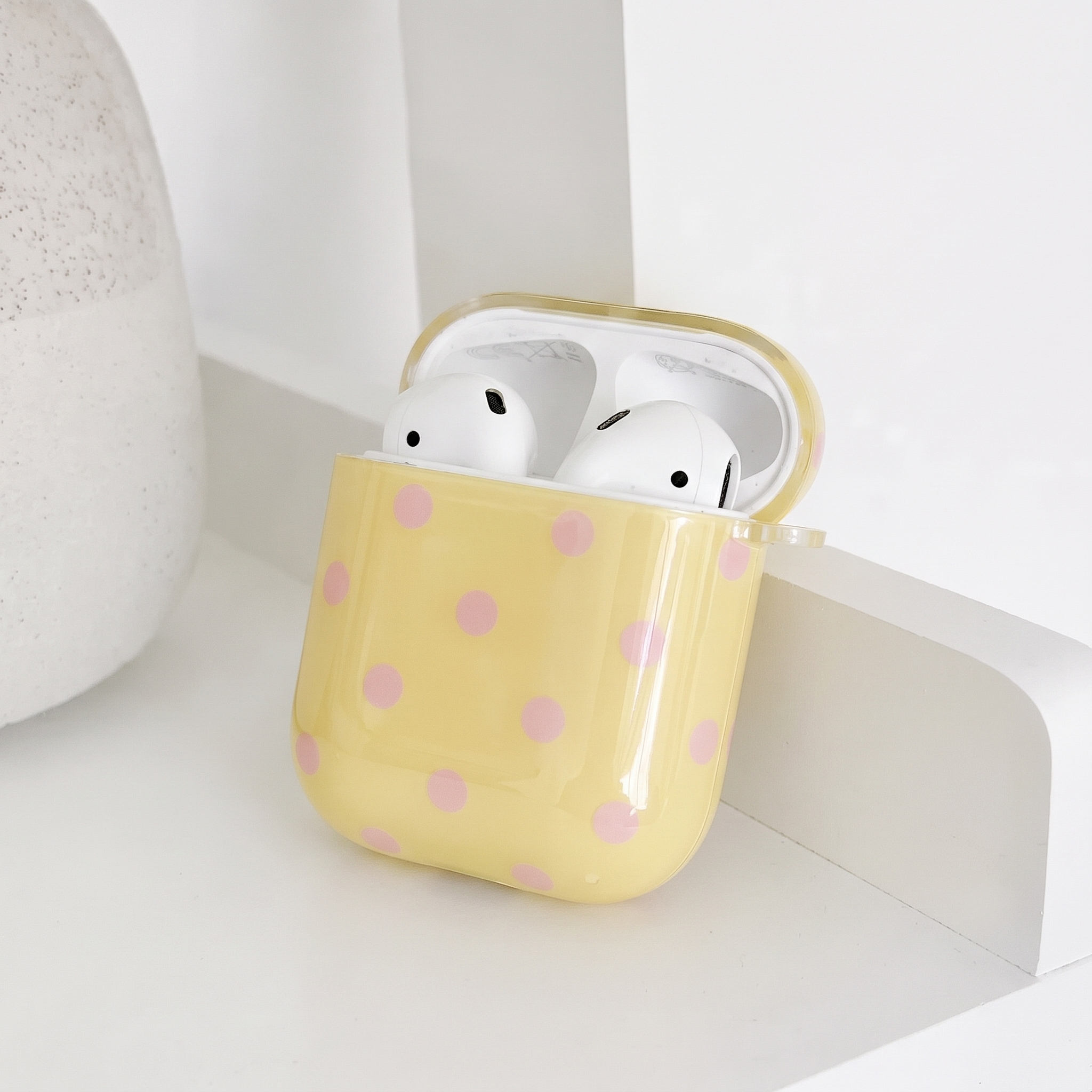 Pale yellow AirPods Case with baby pink polka dots. Showing the inside.
