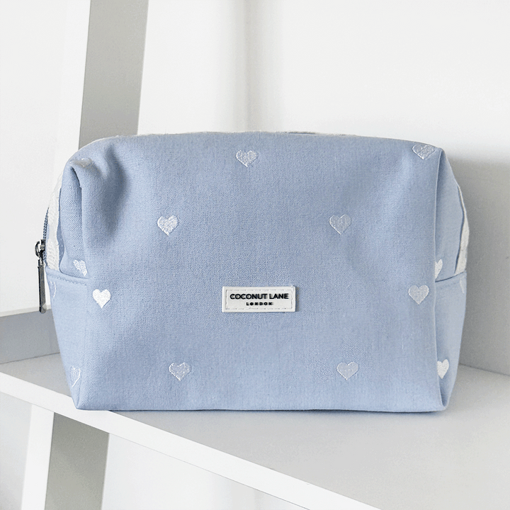 Blue fabric Makeup Bag with embroidered heart design and white lace trim.