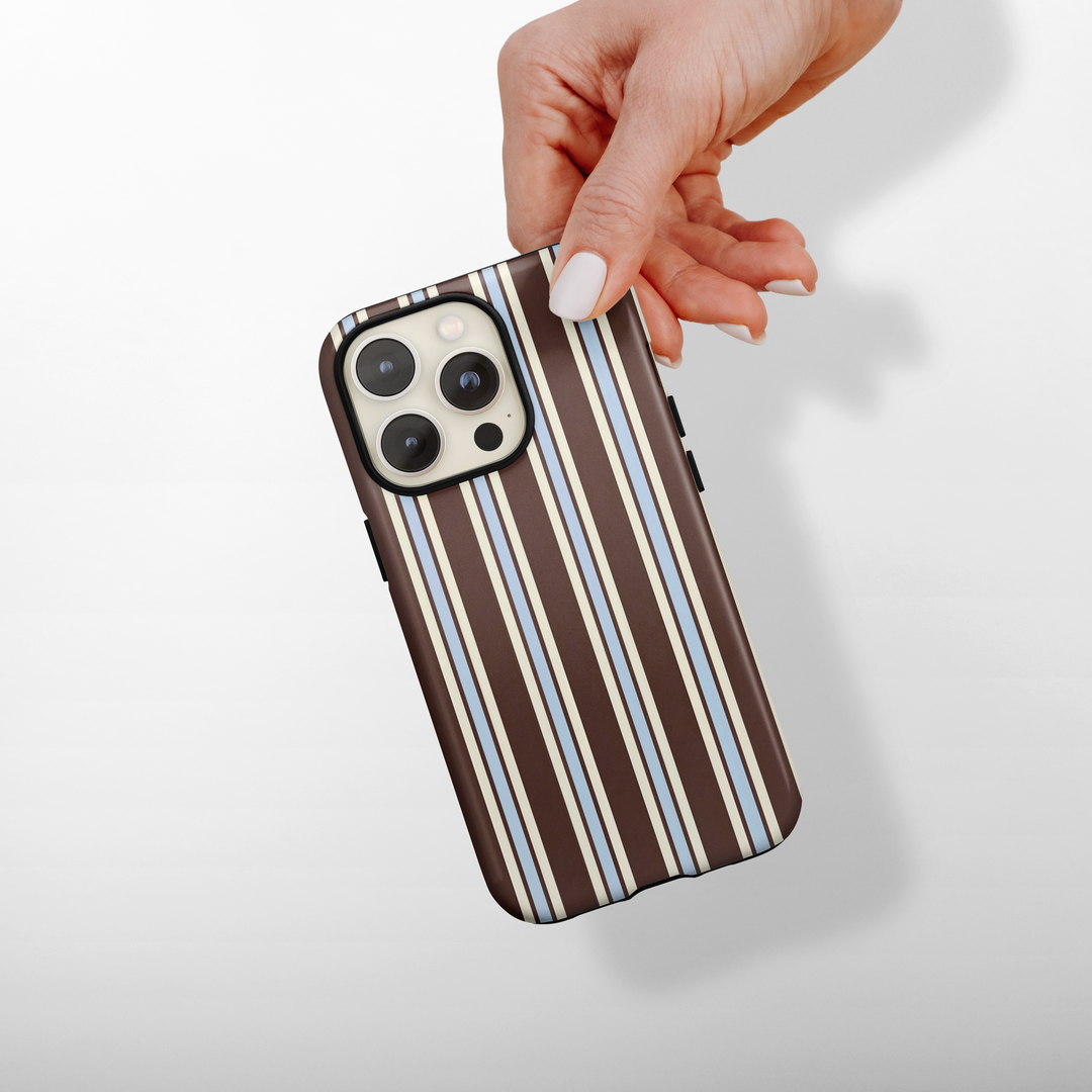 Brown Coconut Lane Tough MagSafe® Phone Case with vertical blue stripes held in a hand.