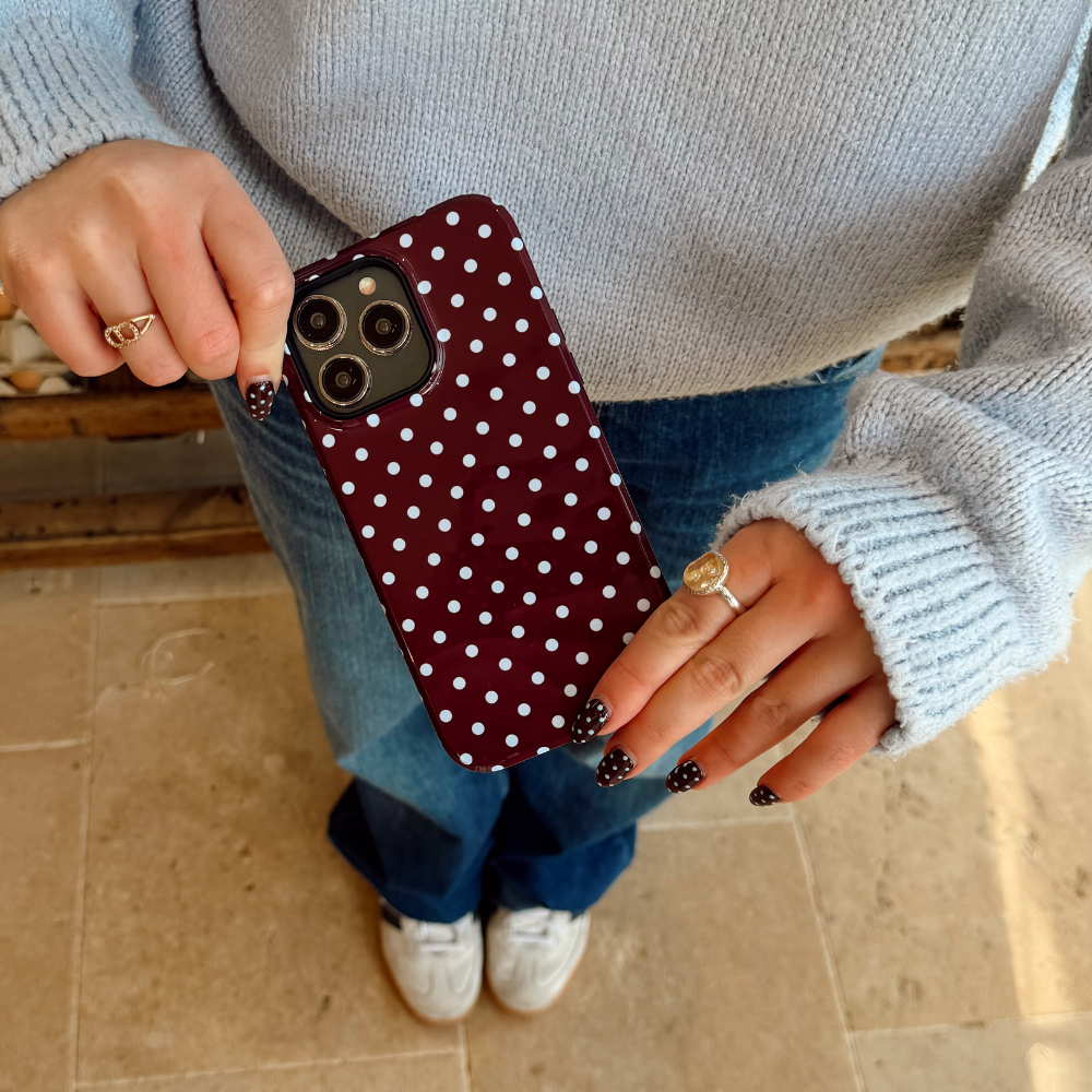 Girl holding her brown and blue polka dot phone case in hand wearing all blue in a farmshop
