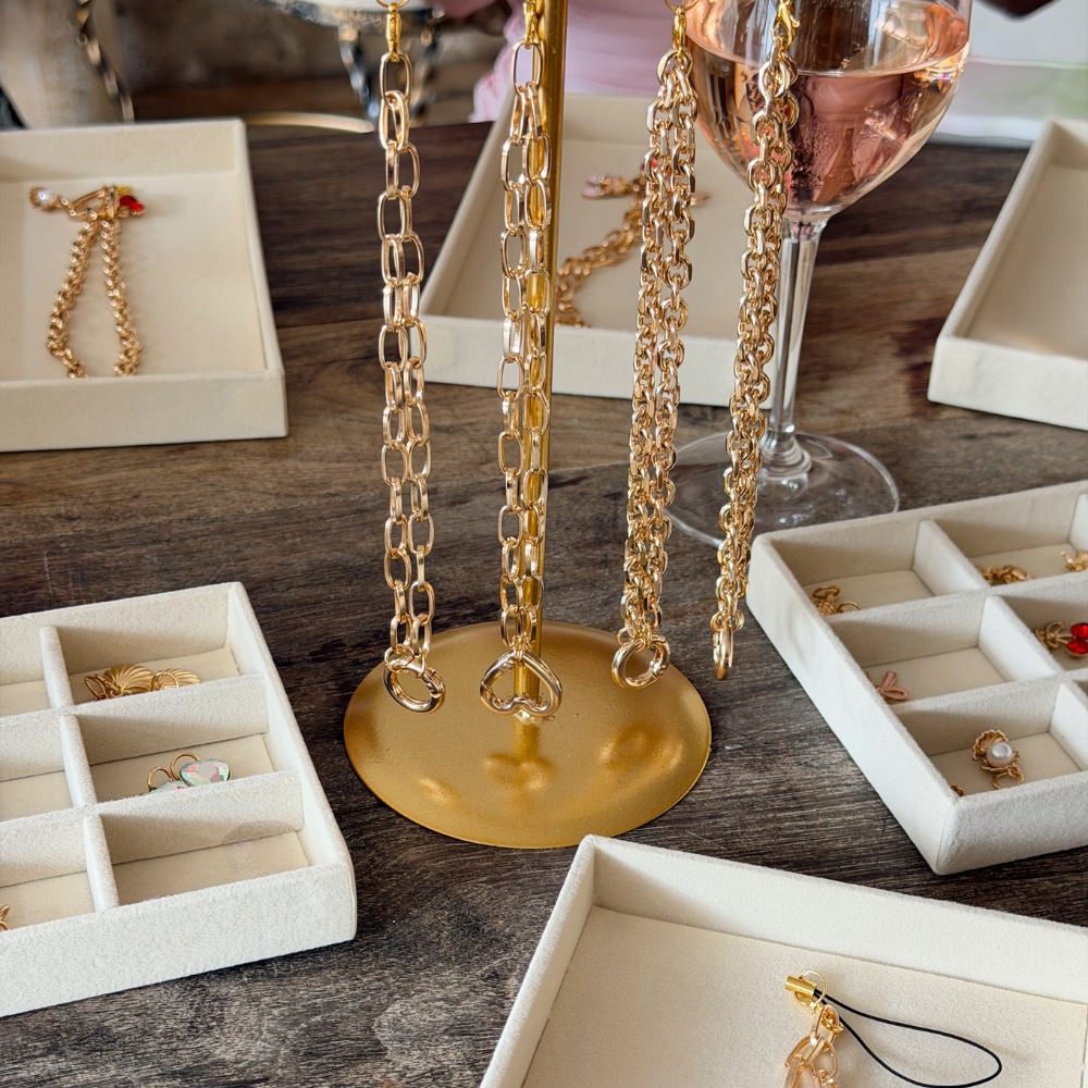 Gold phone straps on a gold stand with jewelry boxes in the background