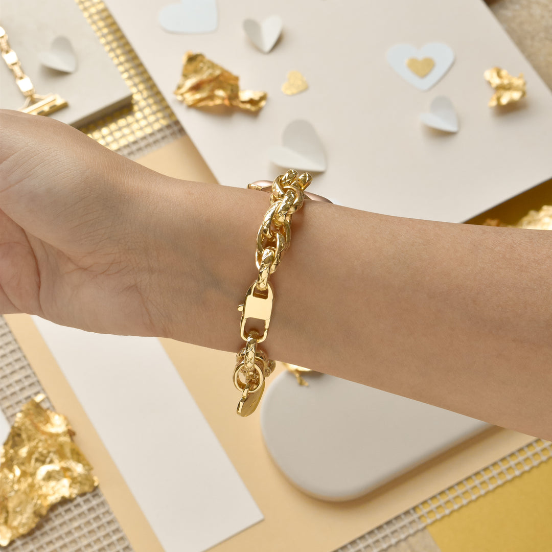 A wrist adorned with the Coconut Lane Chain Bracelet Apple Watch Strap in Gold, against a background featuring scattered gold foil pieces and white paper hearts. The surface underneath includes textured beige and white materials, creating a scene that evokes a sense of elegance and romance.