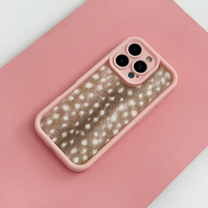 A phone case with pink edging and brown fawn-print center featuring white spots, shown on a phone against a solid pink background.