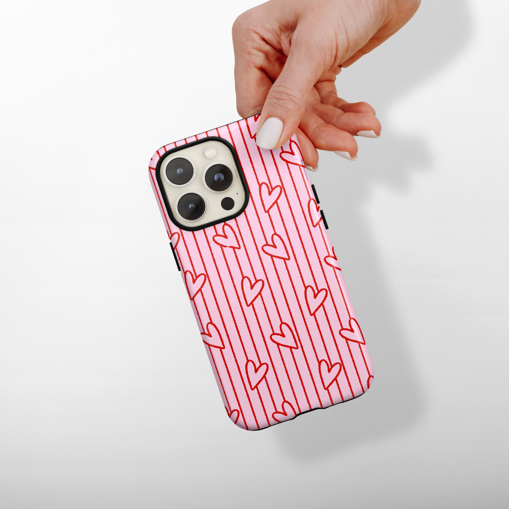 Phone case with heart pattern held by a hand on a light background
