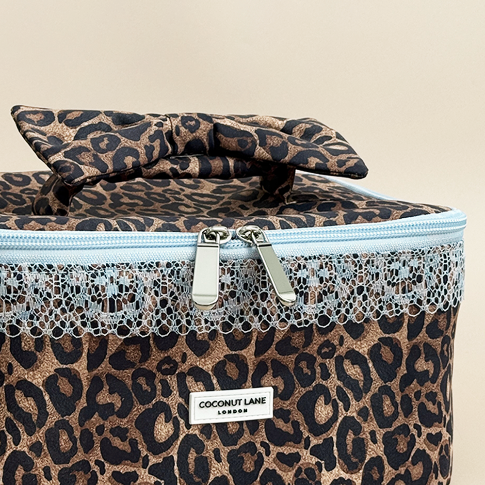 Detailed front view of Coconut Lane Leopard Lace vanity case featuring a leopard print bow handle, pale blue lace trim and silver double zips.