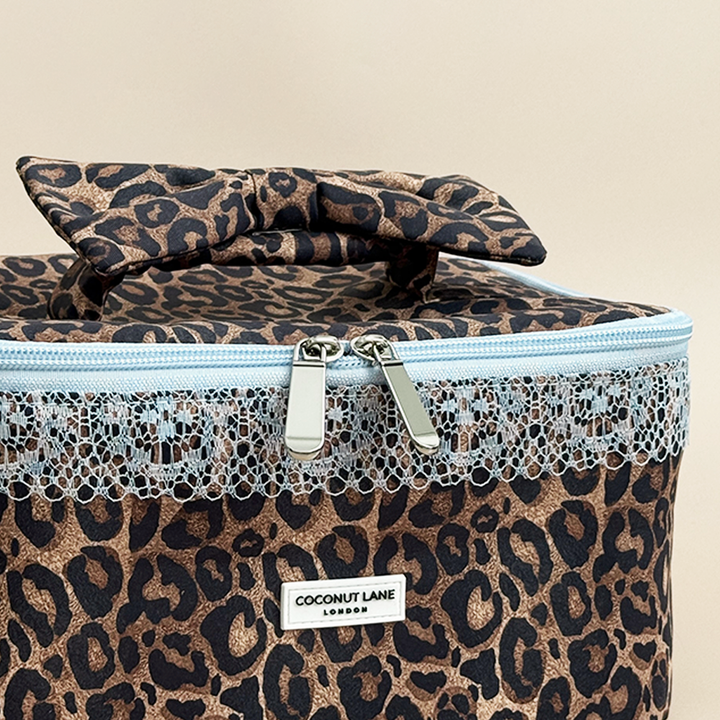 Detailed front view of Coconut Lane Leopard Lace vanity case featuring a leopard print bow handle, pale blue lace trim and silver double zips.