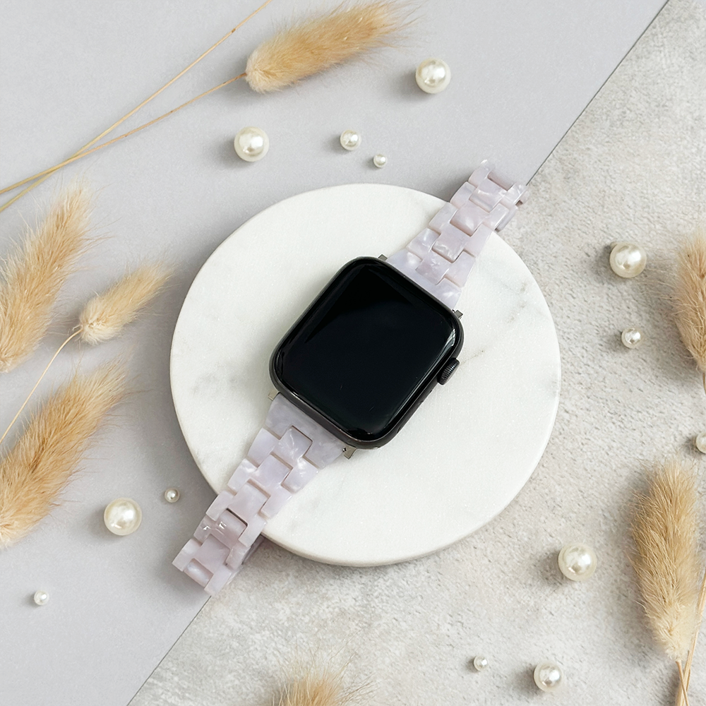 Pale pink Slim Luxe Pearl Apple Watch strap on marble, accented by pearls and dried grasses.