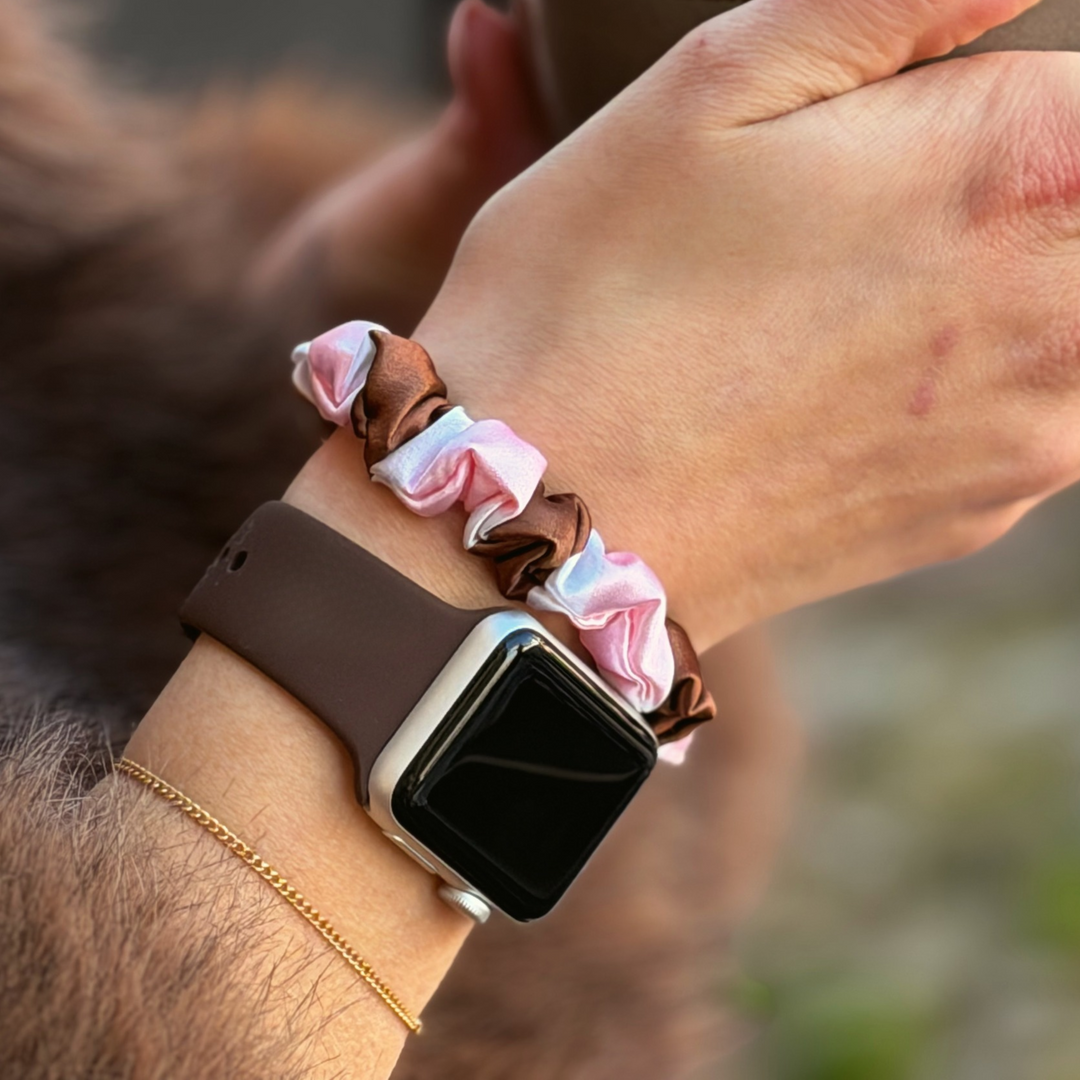 Coconut Lane NAKD Apple Watch strap in chocolate brown on a woman's wrist alongside the cocoa and pink stripe satin scrunchie in brown, pink and white stripes.