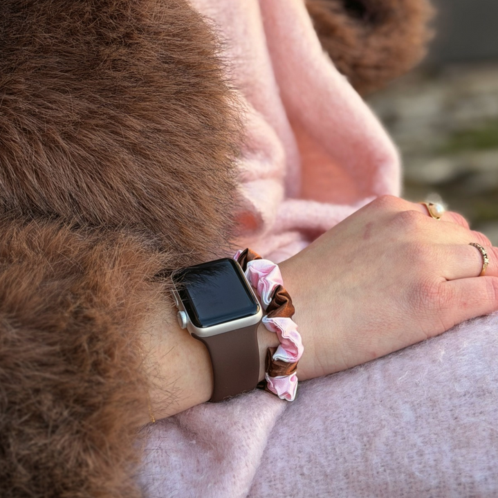 Coconut Lane NAKD Apple Watch strap in chocolate brown on a woman's wrist alongside the cocoa and pink stripe satin scrunchie in brown, pink and white stripes.