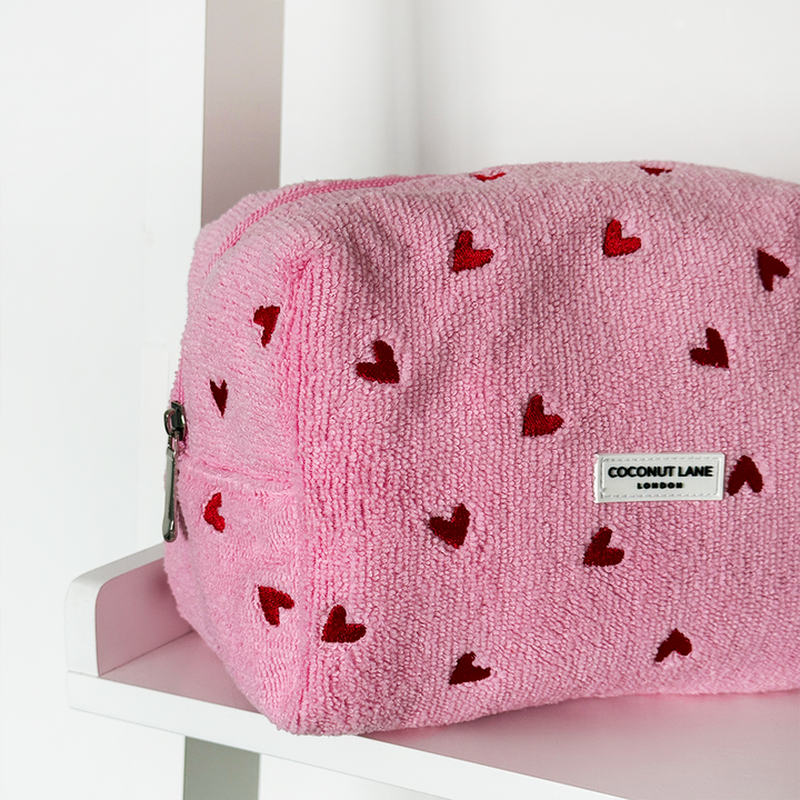 Pink pouch with red heart patterns on a white surface
