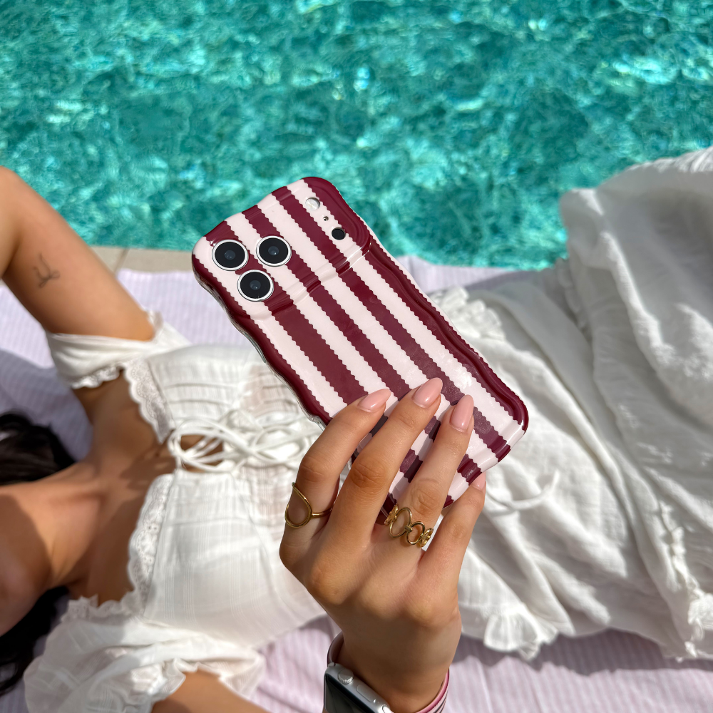 Girl taking a selfie by the pool holding wavy blushberry scallop stripes phone case