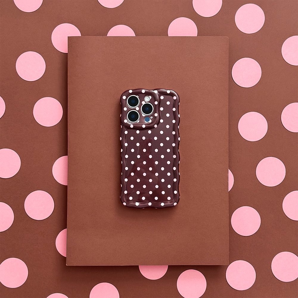 Brown phone case with wavy edges and polka dots on a brown notebook with pink polka dots.