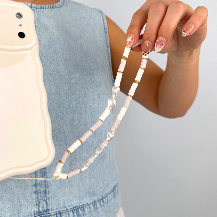 Girl holding beaded nude and pearl phone strap wearing blue denim top