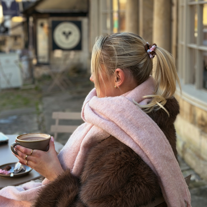 Woman with blonde hair, sat with a hot chocolate, wearing a Satin hair scrunchie in a brown, pink and white striped design.